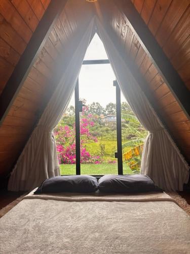 a bed in a room with a large window at Hop Village in Praia do Rosa