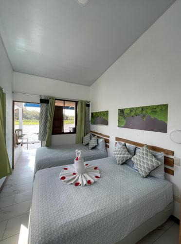 a bedroom with two beds and a balcony at Hotel Pura Natura Riverside Tortuguero in Tortuguero