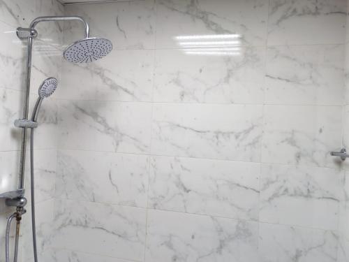 a bathroom with a shower with white marble walls at Elegant Sea View Apartment in Ajman 