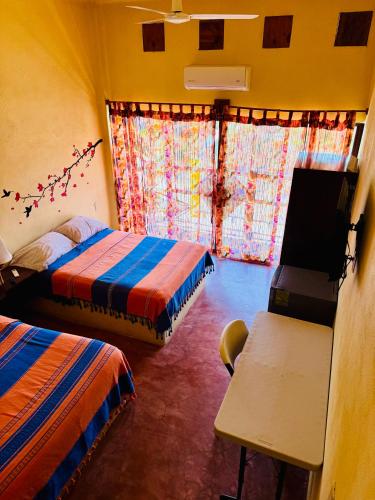 a bedroom with two beds and a desk and a window at Casa Colibri La Punta in Brisas de Zicatela