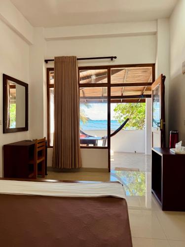 a bedroom with a bed and a view of the ocean at Rupas Hotel in Arugam Bay