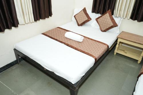 two twin beds in a room with a table at Hotel laxminarayan niwas in Shirdi