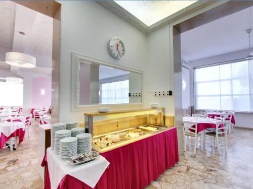 ein Restaurant mit Tischen und einer Uhr an der Wand in der Unterkunft Hotel Promenade Universale in Cesenatico