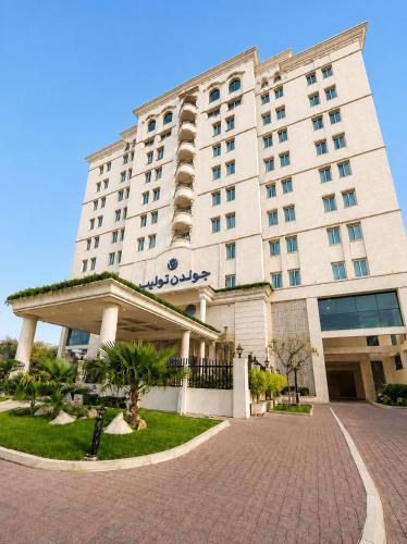 a large white hotel building with a brick driveway at Golden Tulip Al Khobar in Al Khobar