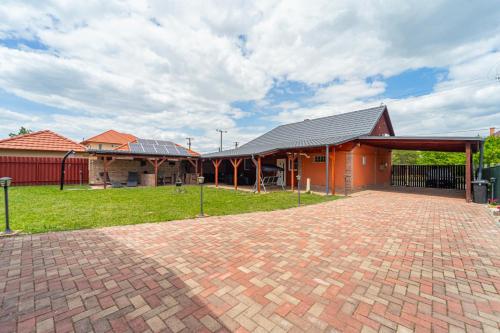 a building with a brick driveway in front of it at Indok Vendégház in Abádszalók