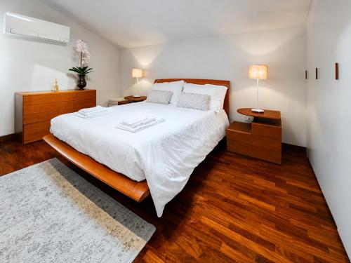 a bedroom with a large white bed and wooden floors at Casa di Iaio - Wi-Fi Netflix Home Cinema in Gorizia