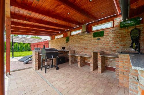 a patio with a grill and a brick wall at Indok Vendégház in Abádszalók