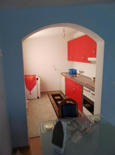 a small kitchen with red cabinets and a glass table at 3 Zimmer Wohnung in Sutomore
