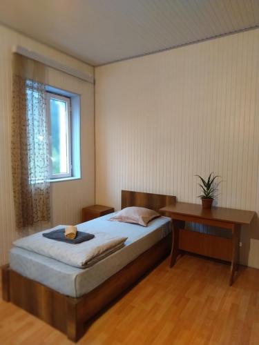a bedroom with a bed and a table and a window at Edle Tropfen in Tqibuli