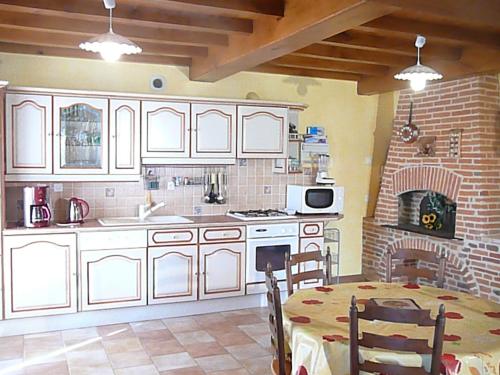 a kitchen with white cabinets and a table and a fireplace at Domaine des Charmilles in Mantenay-Montlin