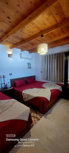 a bedroom with two beds and a wooden ceiling at Moroohouse in Dahab