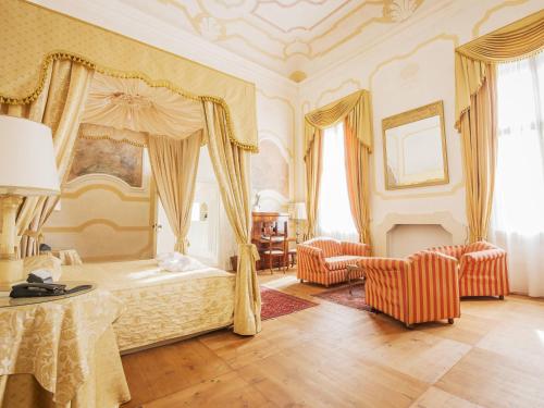 a bedroom with a canopy bed and two chairs at Hotel Villa Cornér della Regina - Buongiorno! Hotels in Vedelago