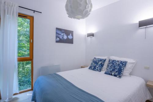 a white bedroom with a bed with blue pillows at Les Charmes C18 - Le Val Joly in Eppe-Sauvage