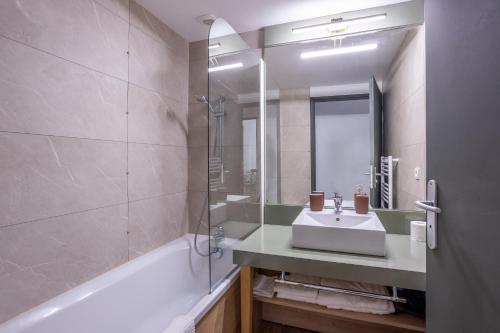 a bathroom with a sink and a tub and a mirror at Les Charmes C18 - Le Val Joly in Eppe-Sauvage