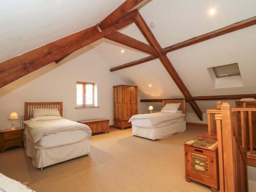 a attic bedroom with two beds and wooden beams at Riverside Barn in Gilwern