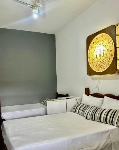 three beds in a room with white sheets at Pousada MG in Tiradentes