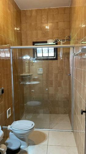 a bathroom with a glass shower with a toilet at Pousada MG in Tiradentes