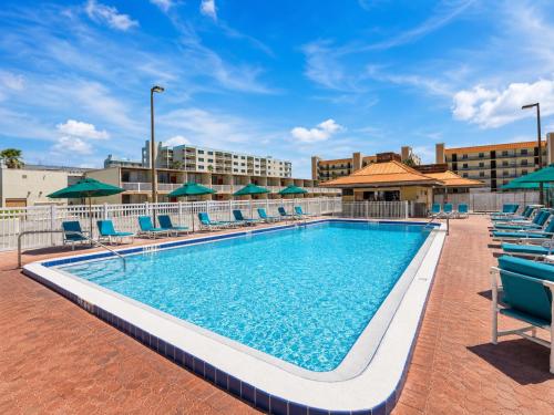 a pool at a hotel with chairs and umbrellas at Ocean Landings Resort Cocoa Beach Port Canaveral in Cocoa Beach
