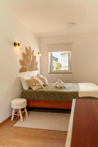 a bedroom with a bed with a window and a stool at SuCaSa Full house with terrace 5 min from centre in Coimbra