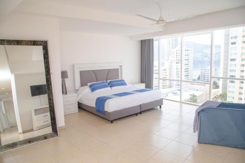 a bedroom with a bed with blue pillows and a mirror at Ocean View Condo with Resort Amenities in Acapulco