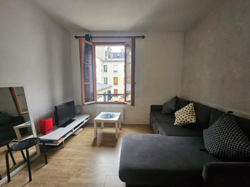 a living room with a couch and a tv at Hébergement SARAH in Paris