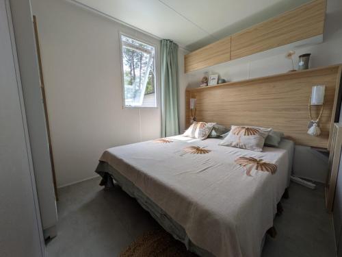 a bedroom with a large white bed with a window at Bungalow mahi-mahi in Lacanau