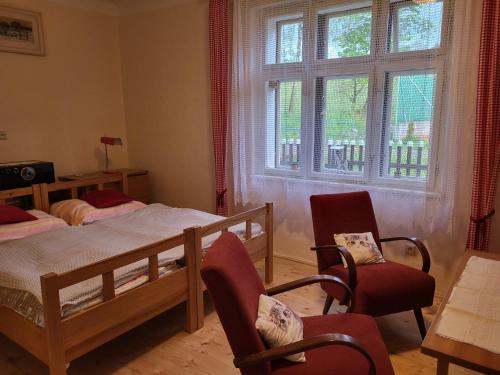 a bedroom with two beds and two chairs and a window at Domek U hřiště in Hlinsko