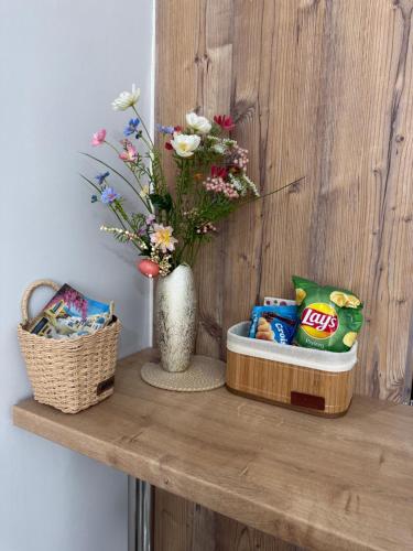 a wooden shelf with a vase with flowers and chips at Eleni’s Mountainview Central Studio by the Sea in Loutraki