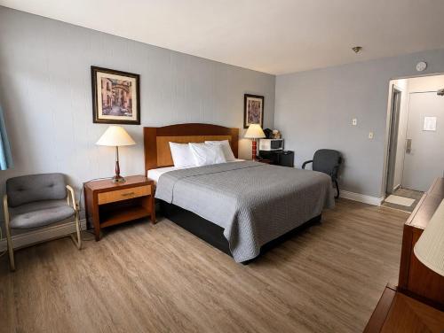 a hotel room with a bed and a chair at Belmont Inn in Sudbury