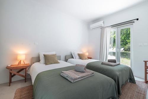 two beds in a white room with a window at Quinta da Berlica - Alentejo in Estremoz