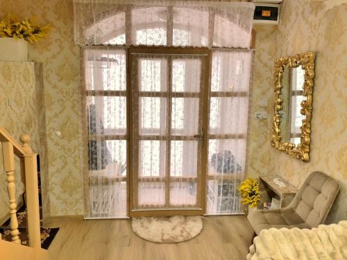 a living room with a large window and a chair at Jázmin Apartman in Debrecen
