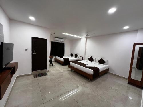a living room with two beds and a flat screen tv at Hotel Church Way Inn in Velankanni