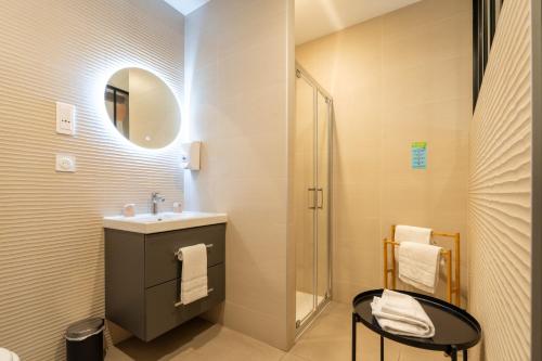 a bathroom with a sink and a shower with a mirror at Hôtel Le Blason in Amboise