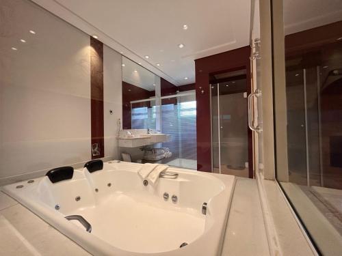 a large white bath tub in a bathroom at Pousada Annecy - CAPIVARI Fácil acesso ao centrinho e Baden Bar in Campos do Jordão