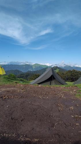 a tent on top of a hill with mountains in the background at Raghupur trecking camp in Shoja