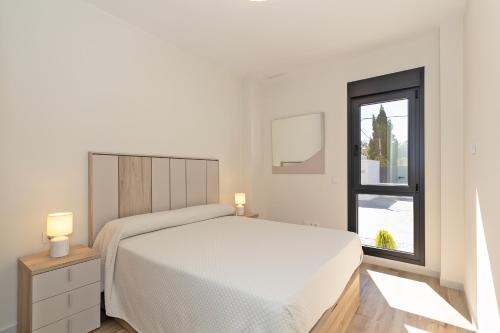 a white bedroom with a bed and a window at Oasis los Lagos in Alginet