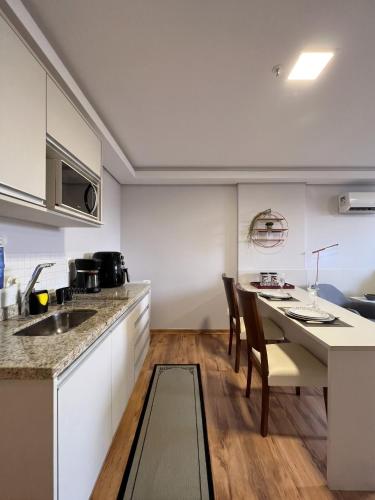 a kitchen with a table and chairs and a counter at Hotel Flat Afonso Pena in Campo Grande
