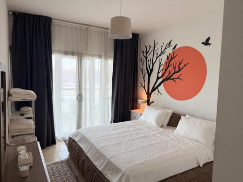 a bedroom with a bed with a tree on the wall at Al Raha Beach modern 1 bedroom near AD airport in Abu Dhabi