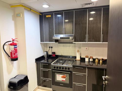 a kitchen with wooden cabinets and a stove top oven at Al Raha Beach modern 1 bedroom near AD airport in Abu Dhabi