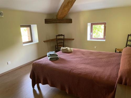 a bedroom with a bed with a red blanket and two windows at La maison de Laujol in Moissac