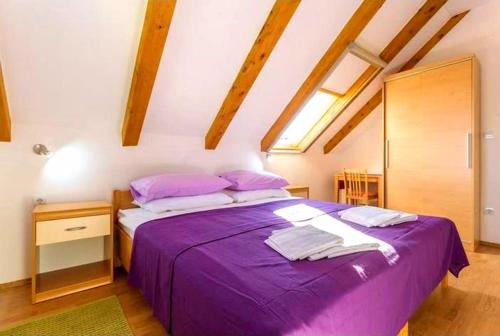 a bedroom with a purple bed in a attic at Sandy Beach Apartments in Koločep