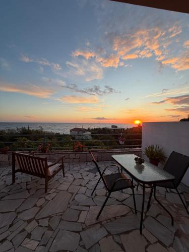 a patio with a table and chairs and the sunset at Olive tree villa in Ligia