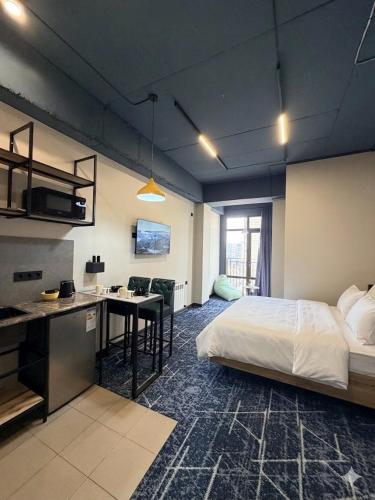 a bedroom with a bed and a desk and a kitchen at Smile Residence Bishkek in Bishkek