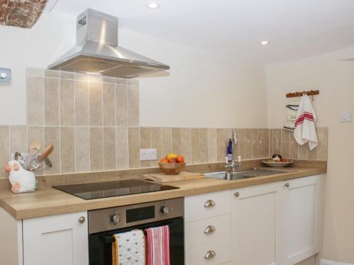 a kitchen with a sink and a stove top oven at Upper Frogpool Cottage in Crediton