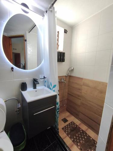a bathroom with a sink and a shower with a mirror at Nina's Cozy Home in Chrani