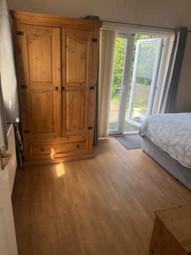 a bedroom with a large wooden cabinet and a bed at Pinfold Holiday Cottage in Laxey