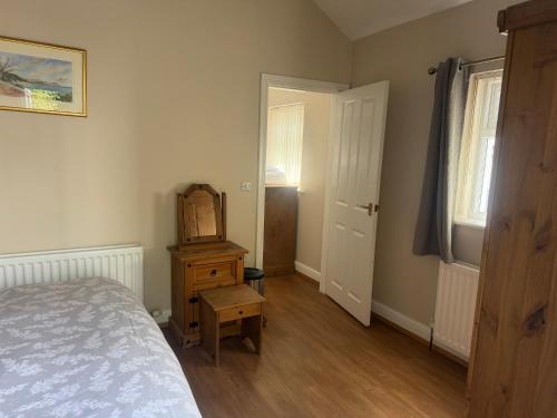 a bedroom with a bed and a dresser and a door at Pinfold Holiday Cottage in Laxey