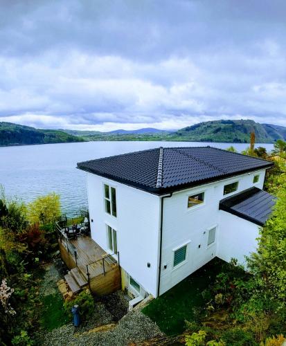 a house with a solar roof on a body of water at Bergen Sunrise Terrace Apartment in Bergen