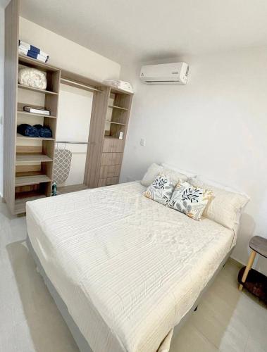 a bedroom with a white bed with pillows on it at Almarena Mazatlan Departamento Nautico in Mazatlán