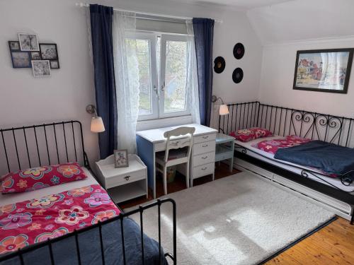 a bedroom with two beds and a desk and a window at Sommerhaus Luisa in Vimmerby
